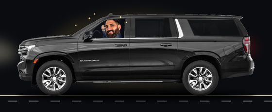 Guillermo smiling and waving inside his 2024 Black Chevrolet Suburban LT